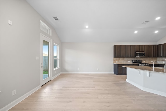 kitchen with a breakfast bar area, stainless steel appliances, lofted ceiling, and light hardwood / wood-style floors