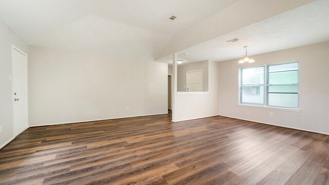 spare room featuring a notable chandelier and dark wood-type flooring