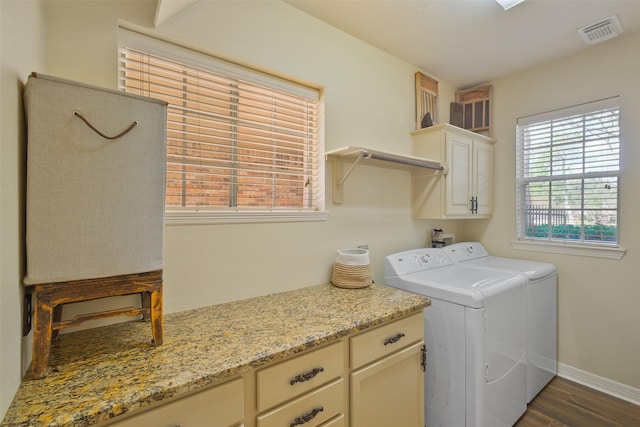 clothes washing area with washer and dryer, dark hardwood / wood-style floors, and cabinets