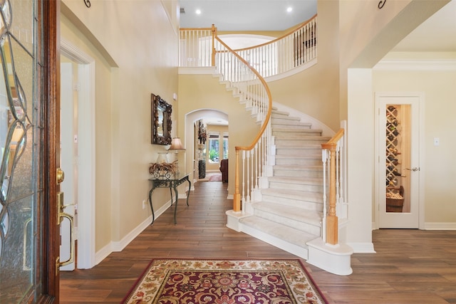 foyer entrance featuring dark hardwood / wood-style flooring, ornamental molding, and a high ceiling