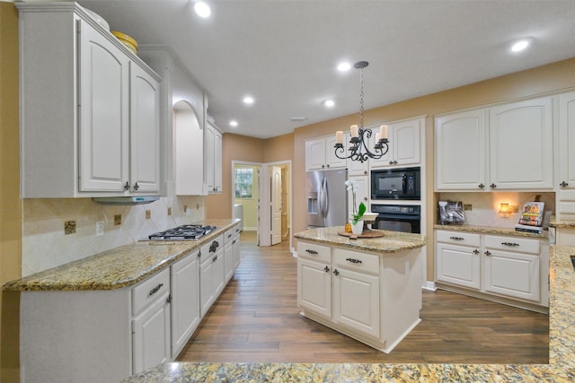 kitchen with black appliances, white cabinets, hanging light fixtures, light stone countertops, and dark hardwood / wood-style flooring