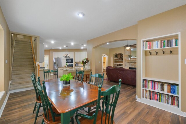 dining area featuring a fireplace, dark hardwood / wood-style flooring, built in features, and ceiling fan