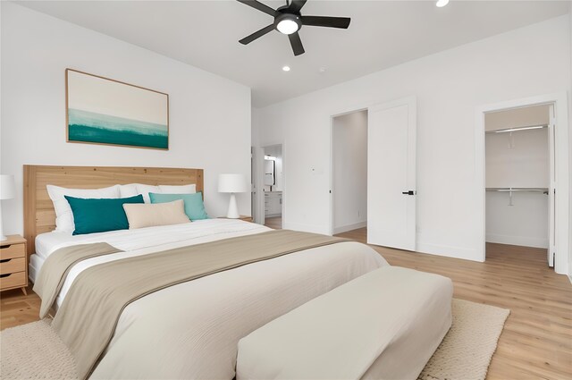 bedroom with wood-type flooring, a walk in closet, a closet, and ceiling fan