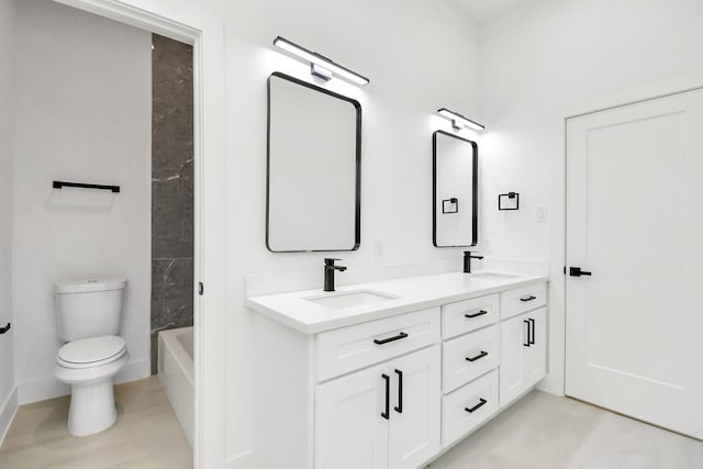 bathroom with double vanity, a sink, and toilet