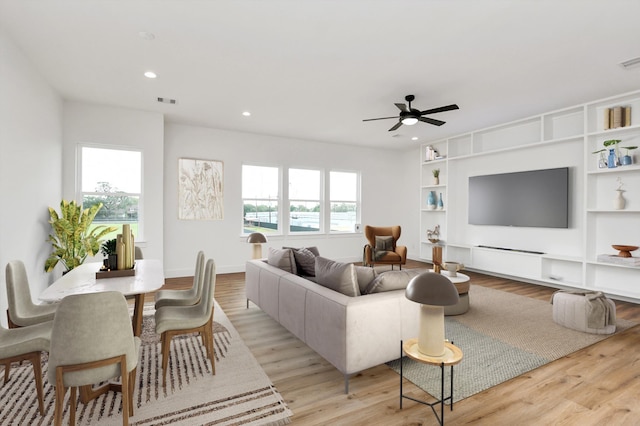 living area featuring light wood finished floors, built in features, a wealth of natural light, and recessed lighting