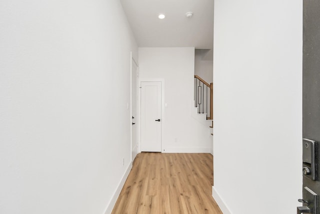 hall featuring light wood-style floors, stairs, and baseboards