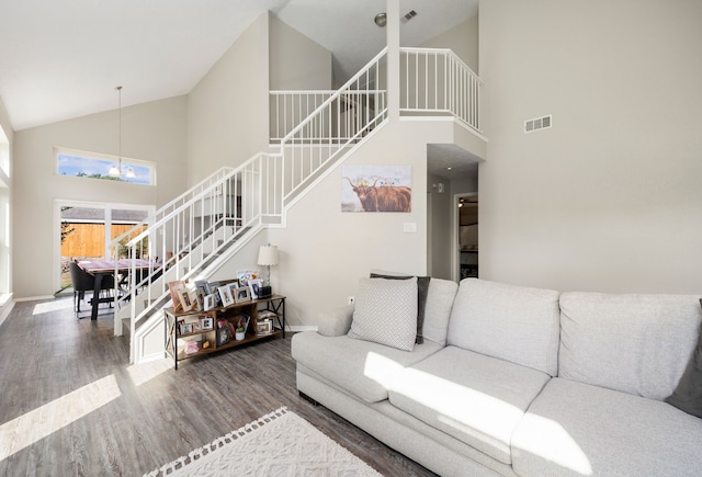 living room featuring hardwood / wood-style flooring, high vaulted ceiling, and a chandelier