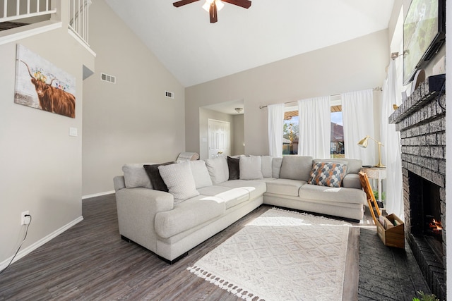 living room with dark wood-type flooring, a brick fireplace, high vaulted ceiling, and ceiling fan