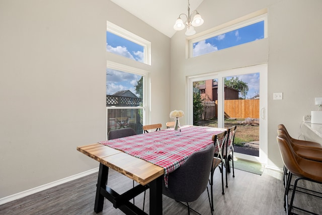 dining space with dark wood-type flooring, high vaulted ceiling, a healthy amount of sunlight, and a chandelier