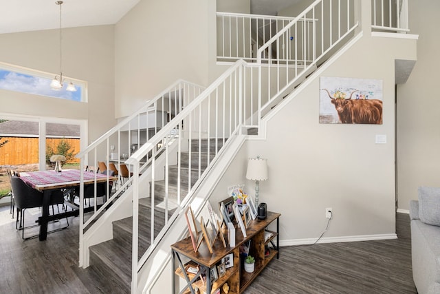 staircase featuring a notable chandelier, high vaulted ceiling, and wood-type flooring