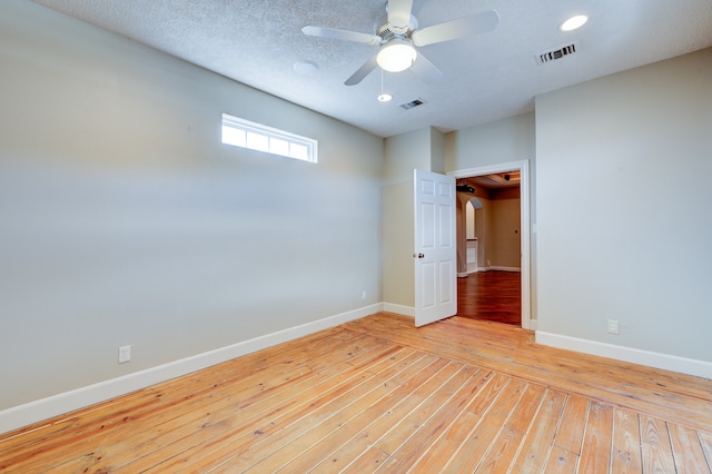 empty room with ceiling fan, a textured ceiling, and light wood-type flooring