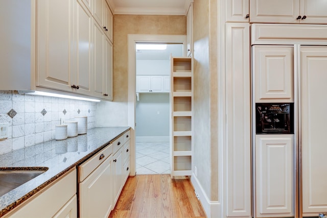 kitchen featuring crown molding, light hardwood / wood-style flooring, white cabinetry, light stone countertops, and decorative backsplash