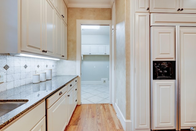 kitchen with crown molding, light stone countertops, white cabinets, decorative backsplash, and light wood-type flooring