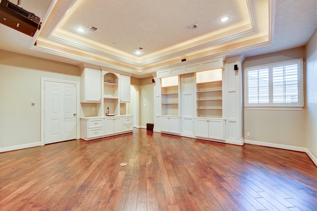 unfurnished living room featuring crown molding, dark wood-type flooring, and a tray ceiling