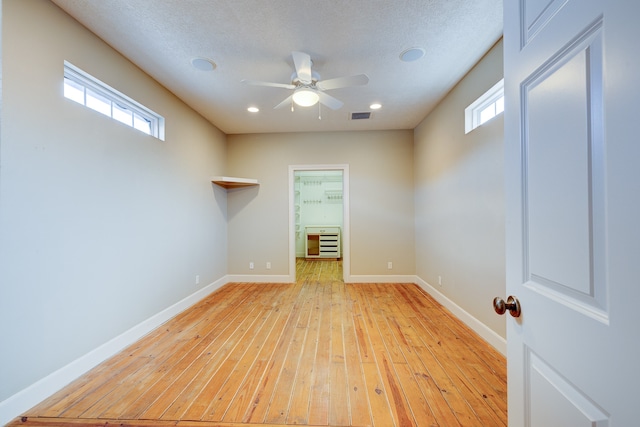 empty room with ceiling fan, a textured ceiling, and light wood-type flooring