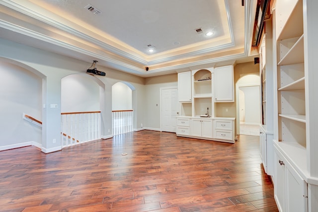 unfurnished living room featuring ornamental molding, a tray ceiling, dark hardwood / wood-style flooring, and sink