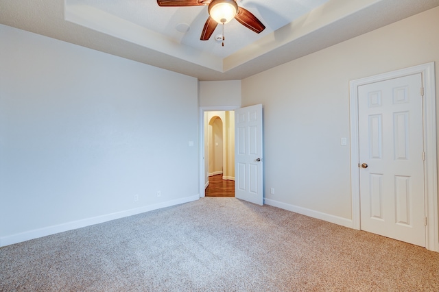 unfurnished room featuring ceiling fan, carpet flooring, and a tray ceiling