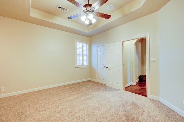 interior space featuring a raised ceiling, ceiling fan, and carpet