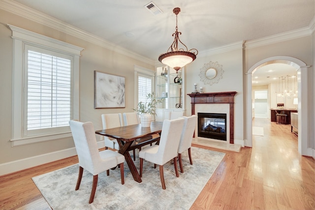 dining room featuring crown molding, a multi sided fireplace, and light hardwood / wood-style flooring