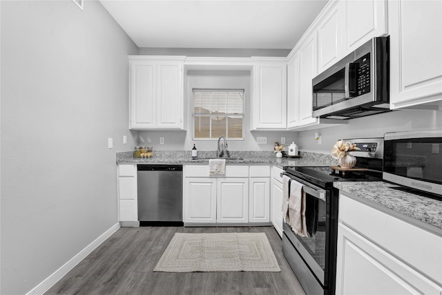 kitchen with sink, appliances with stainless steel finishes, wood-type flooring, and white cabinets