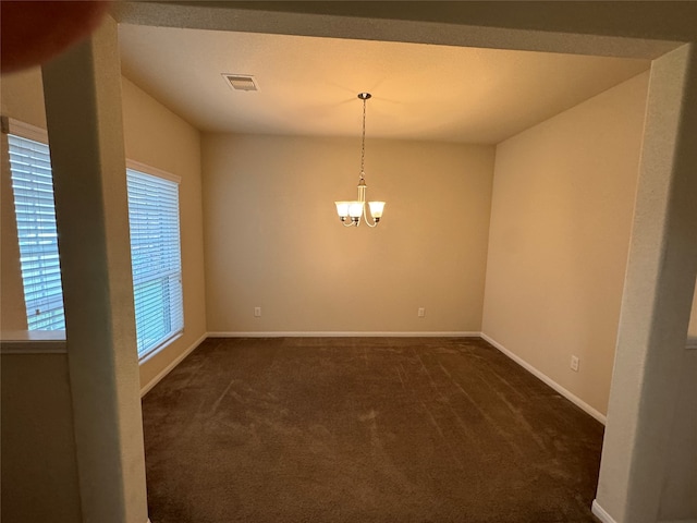 carpeted empty room featuring a notable chandelier