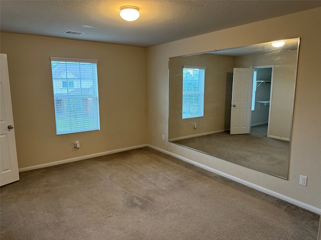 empty room with carpet and a textured ceiling