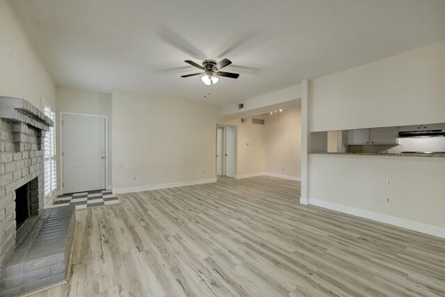 unfurnished living room with a brick fireplace, light hardwood / wood-style floors, and ceiling fan