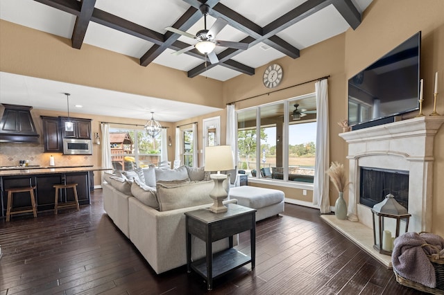 living room featuring beamed ceiling, dark wood-type flooring, ceiling fan with notable chandelier, and coffered ceiling