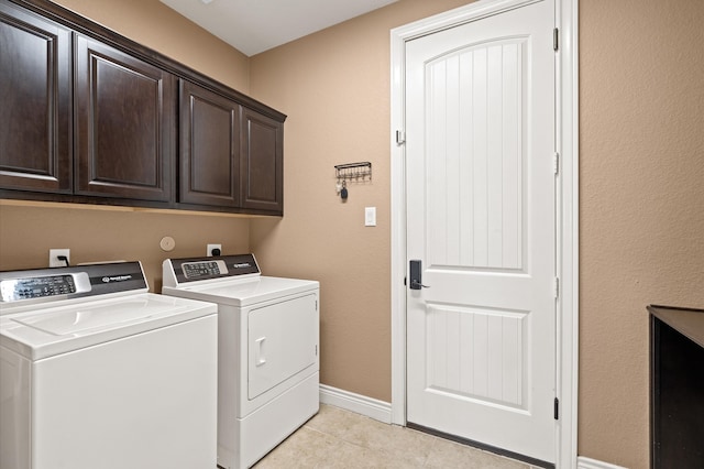 clothes washing area with light tile patterned flooring, cabinets, and washer and clothes dryer