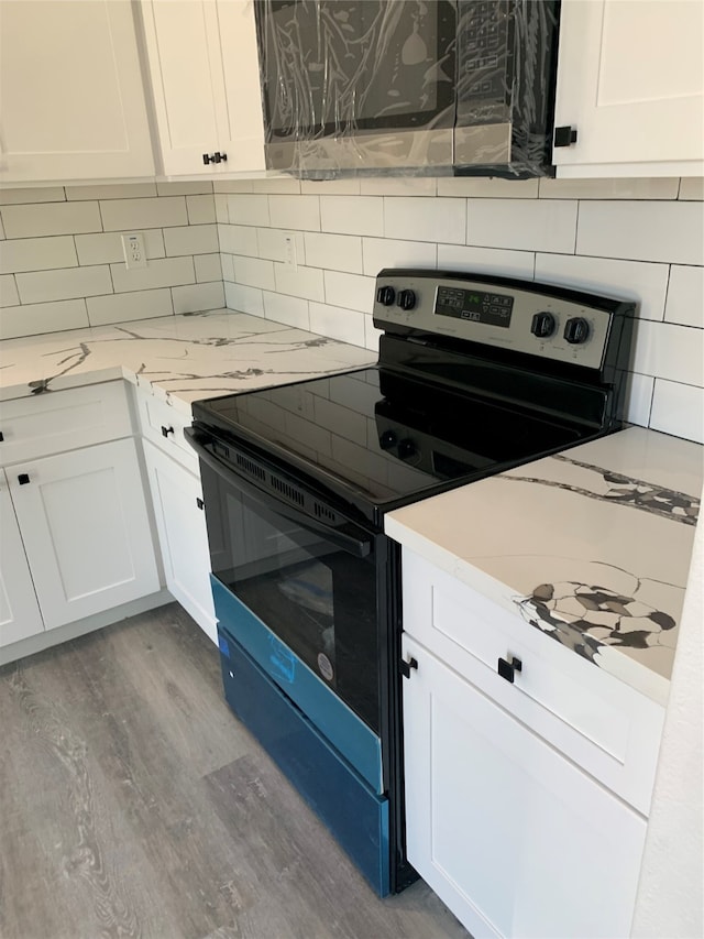 kitchen featuring white cabinetry, black / electric stove, light hardwood / wood-style floors, and tasteful backsplash