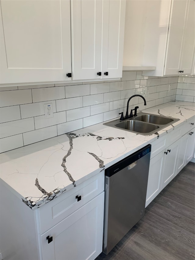 kitchen with dark wood-type flooring, light stone counters, sink, stainless steel dishwasher, and white cabinetry