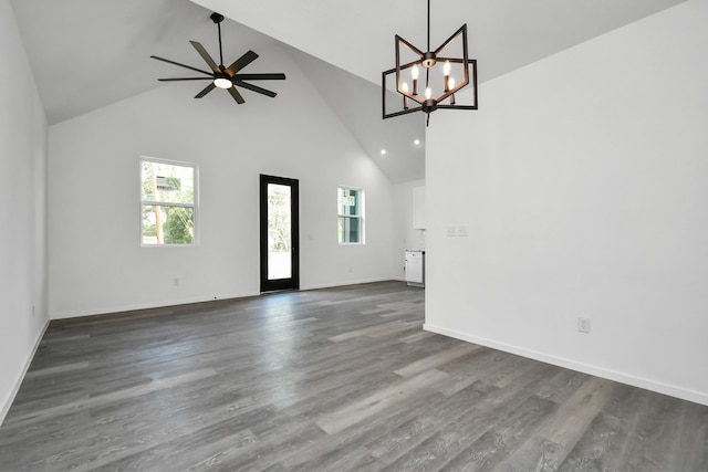 unfurnished living room with high vaulted ceiling, dark hardwood / wood-style flooring, and ceiling fan with notable chandelier