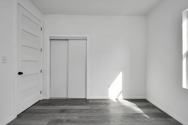 unfurnished bedroom with dark wood-type flooring and a closet