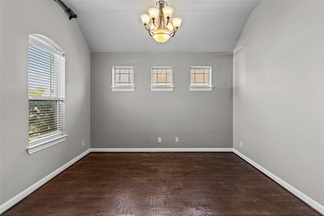 spare room with vaulted ceiling, an inviting chandelier, and dark wood-type flooring