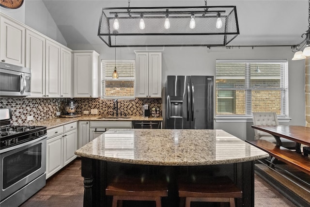 kitchen featuring pendant lighting, white cabinets, decorative backsplash, a kitchen island, and stainless steel appliances