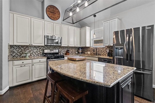 kitchen featuring white cabinetry, sink, a center island, hanging light fixtures, and appliances with stainless steel finishes