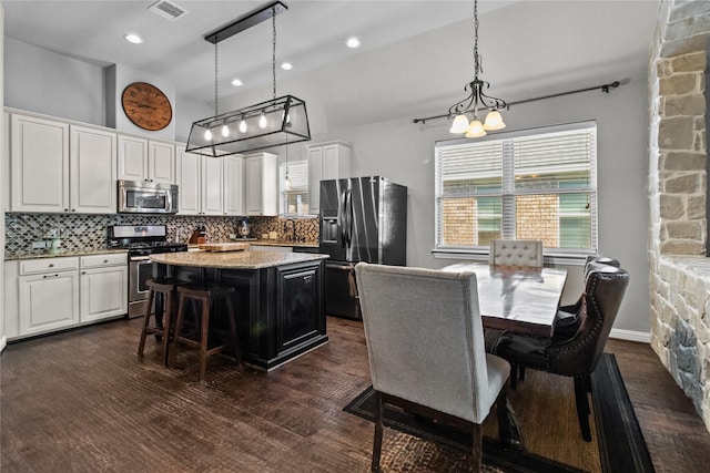 kitchen with a center island, hanging light fixtures, tasteful backsplash, white cabinetry, and stainless steel appliances