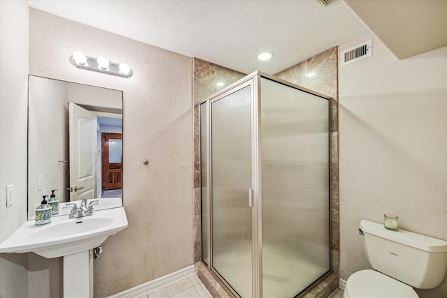 bathroom featuring tile patterned flooring, toilet, a shower with shower door, and sink