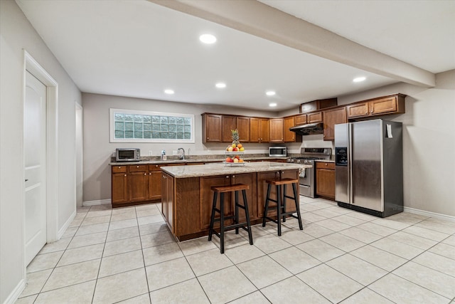 kitchen with light stone countertops, a center island, stainless steel appliances, a kitchen breakfast bar, and light tile patterned floors