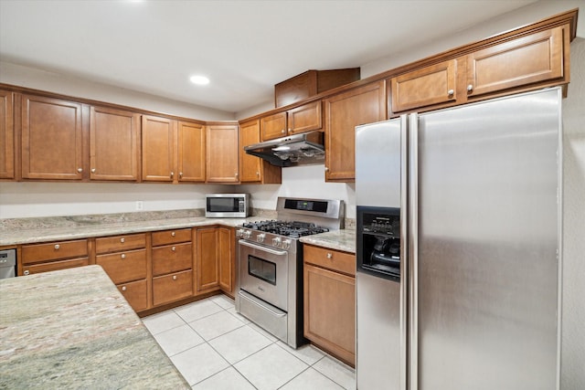 3227 Audley St, Houston, TX 77098 - kitchen with stainless steel appliances, under cabinet range hood, light tile patterned flooring, brown cabinetry, and recessed lighting