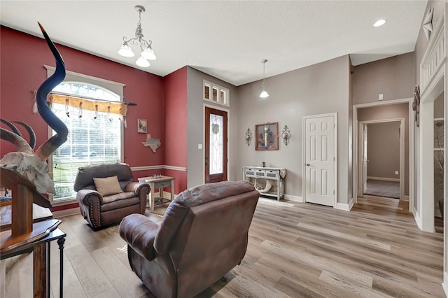 living room featuring light hardwood / wood-style flooring, a textured ceiling, and a chandelier