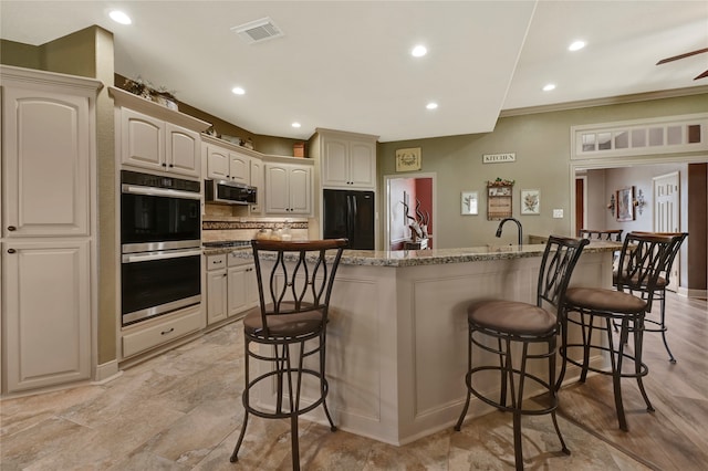 kitchen with a kitchen island with sink, stainless steel appliances, backsplash, and a breakfast bar area