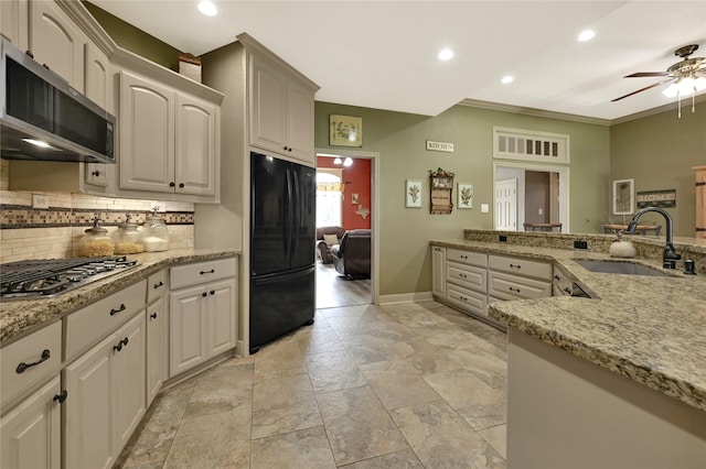 kitchen with appliances with stainless steel finishes, crown molding, light stone countertops, and sink