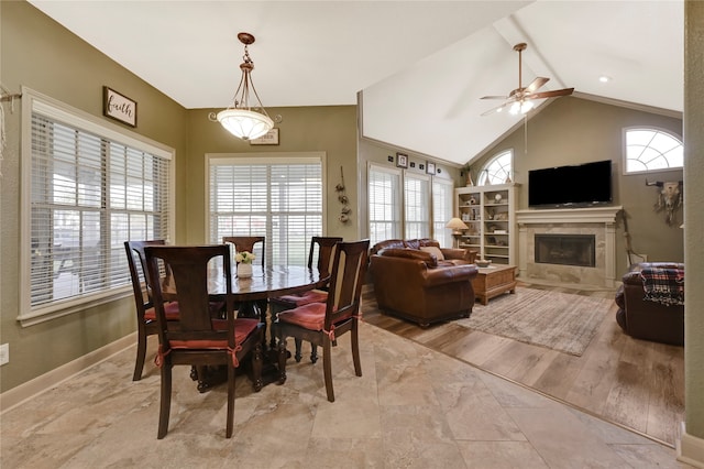 dining space featuring light hardwood / wood-style floors, lofted ceiling, a tile fireplace, and ceiling fan