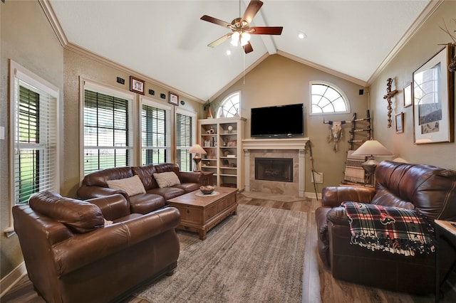 living room featuring lofted ceiling, hardwood / wood-style flooring, a tile fireplace, crown molding, and ceiling fan