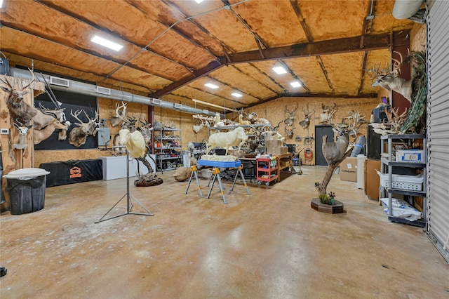 miscellaneous room featuring lofted ceiling, a workshop area, and concrete floors