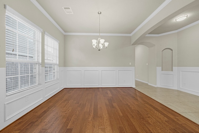 unfurnished dining area featuring crown molding, a chandelier, and wood-type flooring