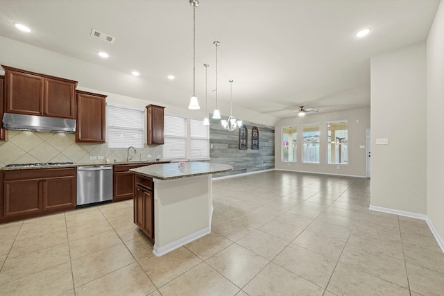 kitchen with a kitchen island, hanging light fixtures, stainless steel appliances, sink, and light stone countertops