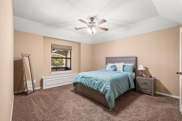 carpeted bedroom featuring a raised ceiling, a textured ceiling, and ceiling fan