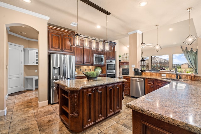 kitchen featuring a kitchen island, appliances with stainless steel finishes, pendant lighting, crown molding, and sink